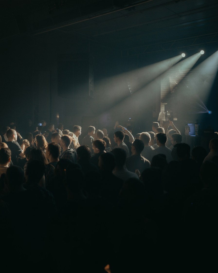 Darts crowd silhouettes against dramatic stage lighting